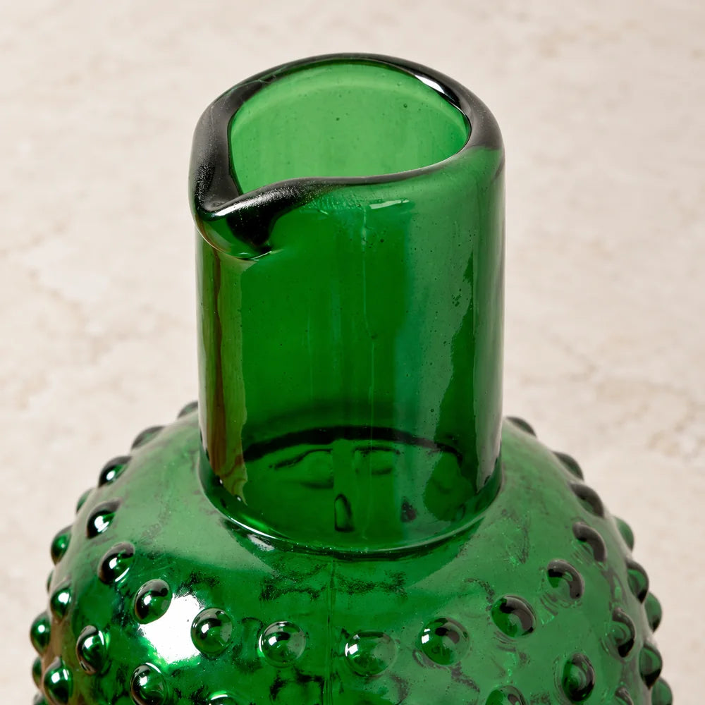 Collo liscio e beccuccio della caraffa in vetro verde, visti leggermente dall’alto.