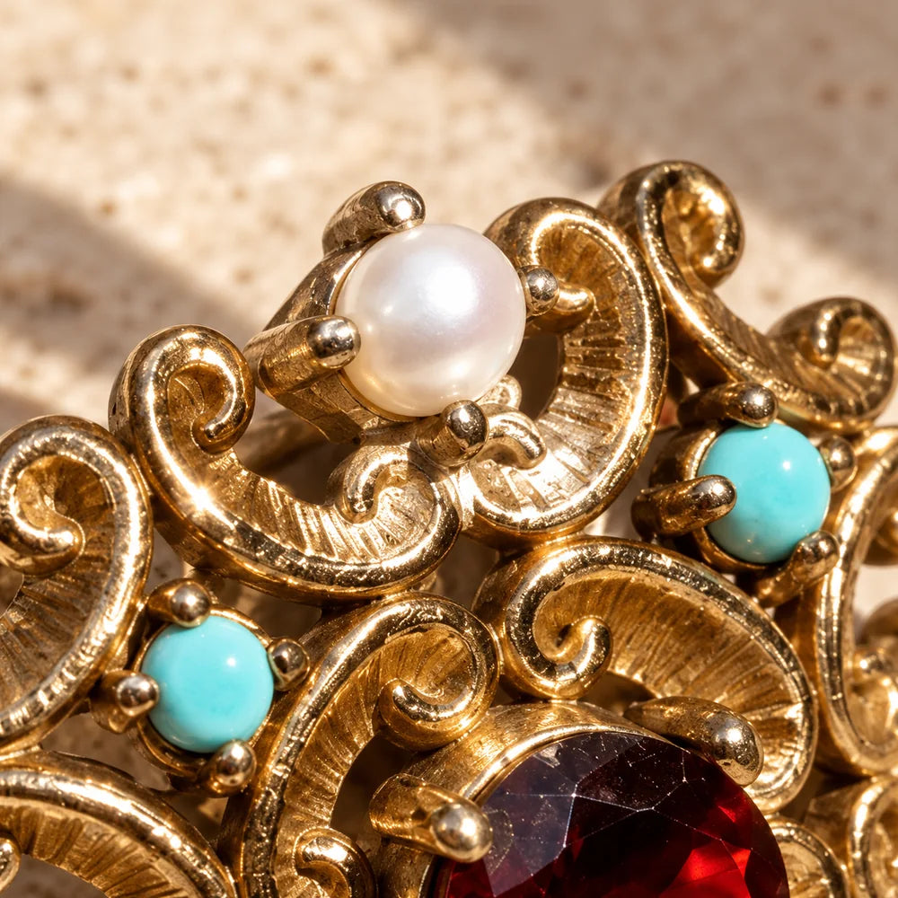 Dettaglio delle perle bianche, delle piccole pietre turchesi e della lavorazione a volute dell’anello d’Este.