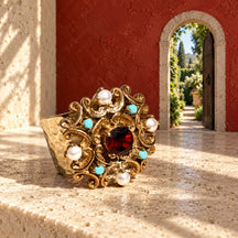 Anello d’Este su un piano avorio, davanti a una piccola porta aperta su un giardino nella parete rossa.