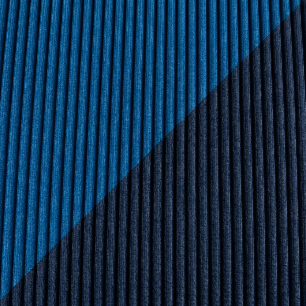 Dettaglio del tessuto plissettato blu notte e della fascia diagonale blu petrolio.