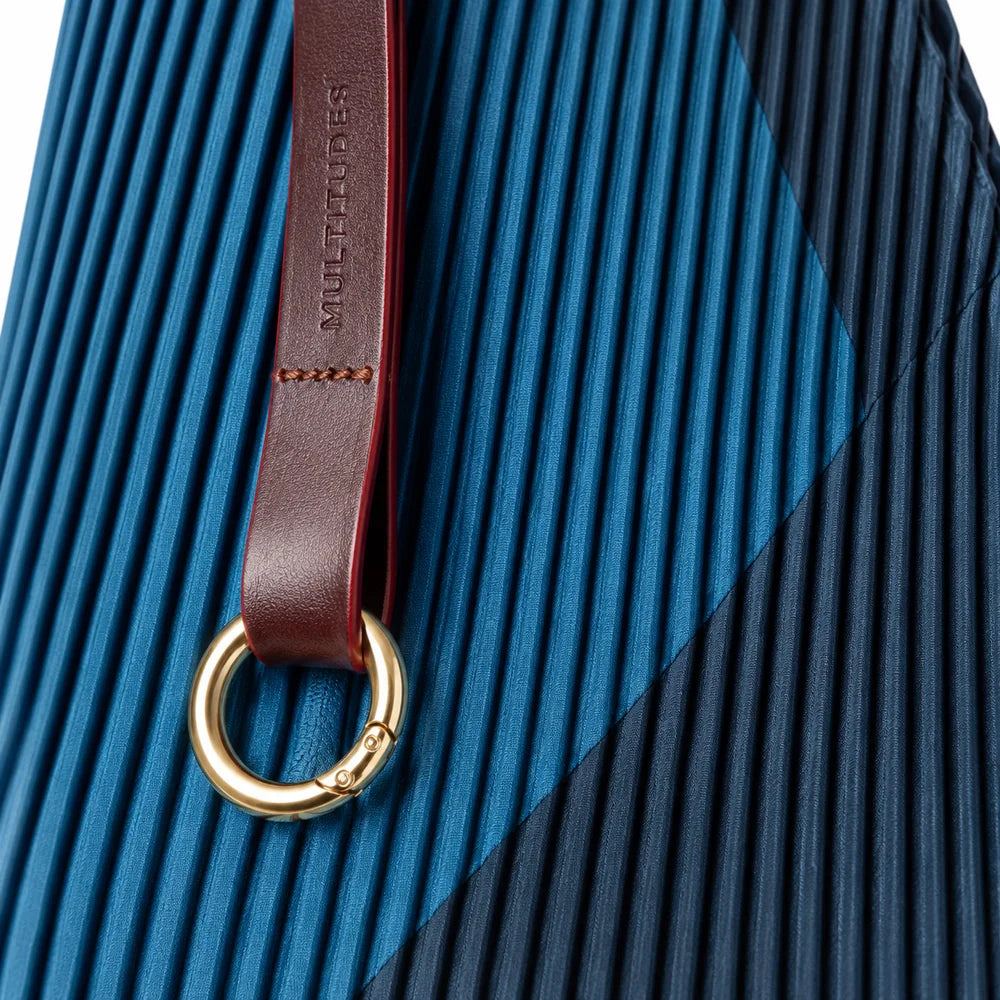 Dettaglio della coda in pelle marrone e dell’anello moschettone dorato della borsa blu.