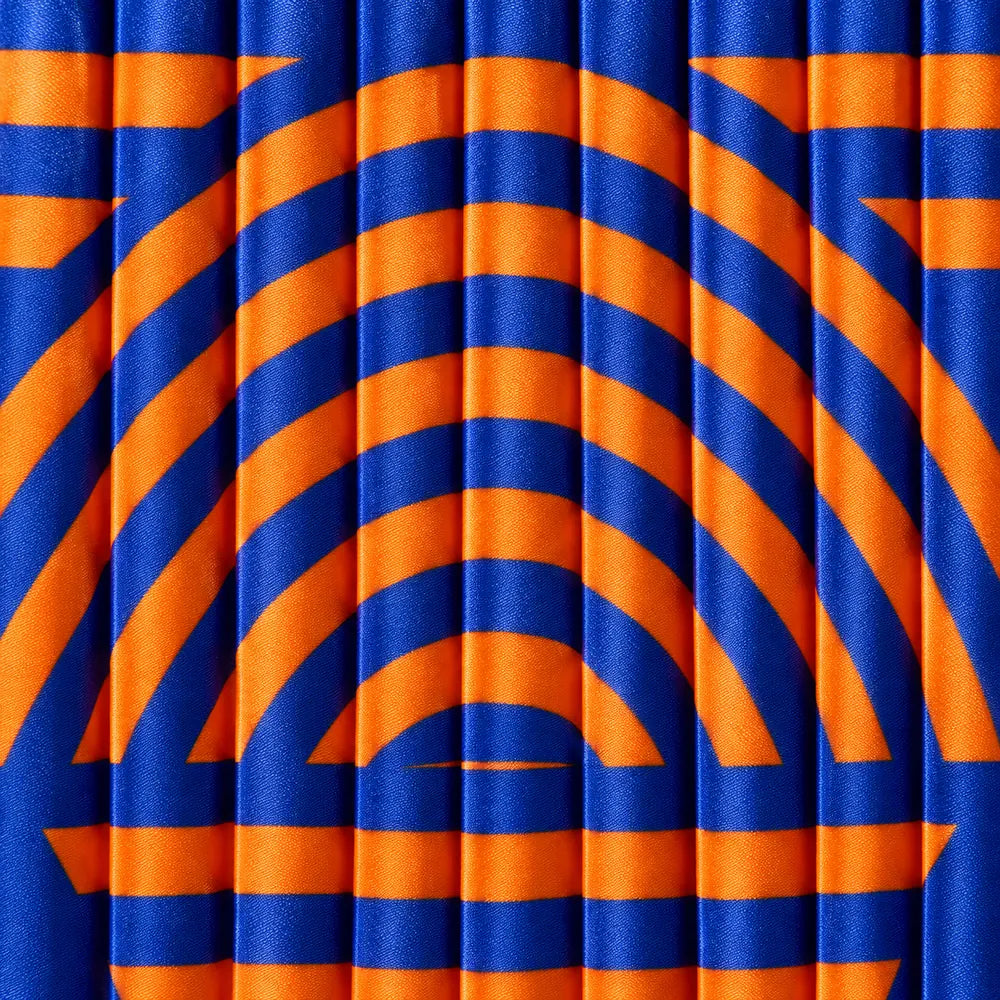 Dettaglio del plissé verticale e delle bande geometriche blu e arancio della tote.
