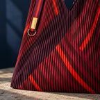 Dettaglio del plissé e delle geometrie rosse e bordeaux della borsa Granata.
