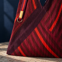Dettaglio del plissé e delle geometrie rosse e bordeaux della borsa Granata.