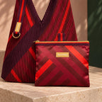Pochette liscia coordinata a Granata, con zip dorata, passante in tessuto ed etichetta del produttore.