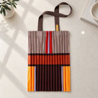 Tote marrone, crema e arancio distesa su pietra chiara, con i manici in gros grain.