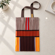 Tote marrone, crema e arancio distesa su pietra chiara, con i manici in gros grain.