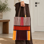 Tote marrone e arancio portata in mano, con la fascia ruggine e le righe sottili visibili.