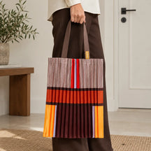 Tote marrone e arancio portata in mano, con la fascia ruggine e le righe sottili visibili.