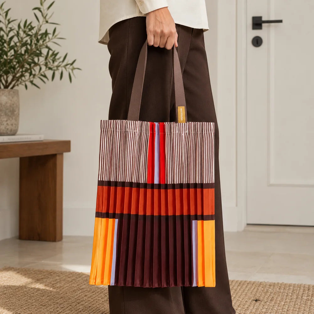 Tote marrone e arancio portata in mano, con la fascia ruggine e le righe sottili visibili.