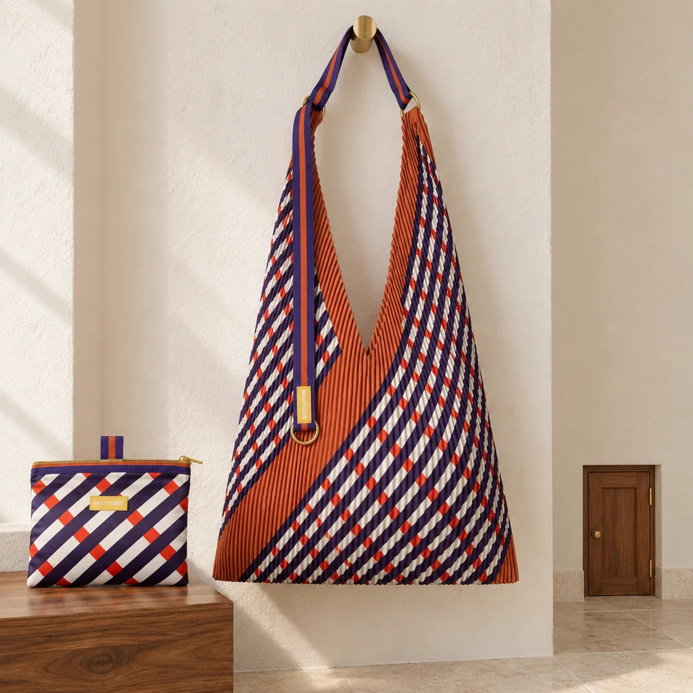 Borsa Intrecci e pochette in un ingresso avorio, accanto a una piccola porta fuori scala.