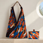 Borsa camouflage blu e arancio con manico in gros grain e pochette coordinata su pietra chiara.