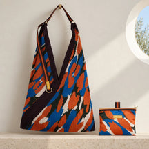Borsa camouflage blu e arancio con manico in gros grain e pochette coordinata su pietra chiara.