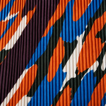 Dettaglio del camouflage arancio, blu, verde scuro e crema sul tessuto plissettato.