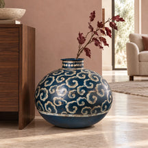 Vaso blu decorativo in ferro collocato a pavimento, con un ramo secco ornamentale.