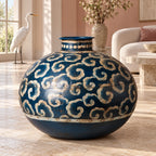 Vaso blu in ferro con motivi beige, in una stanza luminosa con un airone bianco sullo sfondo.