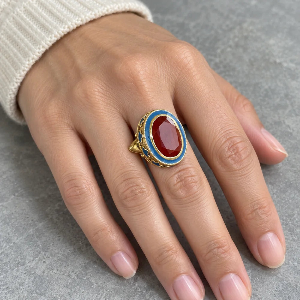 Anello Persia Blu indossato, con il granato rosso e lo smalto azzurro in primo piano.