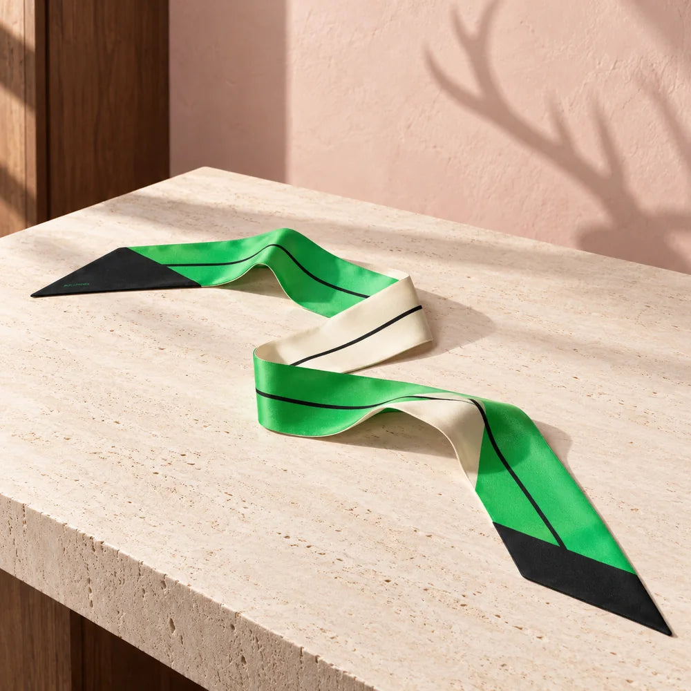 Twilly verde smeraldo e bianco appoggiato su un piano avorio, con punte nere e linea longitudinale nera.