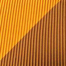 Dettaglio della fascia diagonale giallo arancio sul tessuto plissettato color ocra.