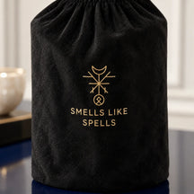 Sacca nera inclusa con simbolo dorato e scritta Smells Like Spells, dettaglio della candela Medio Oriente.