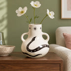 Vaso Incantesimo con tre fiori bianchi in un interno luminoso, con il decoro nero ben visibile.