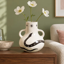 Vaso Incantesimo con tre fiori bianchi in un interno luminoso, con il decoro nero ben visibile.