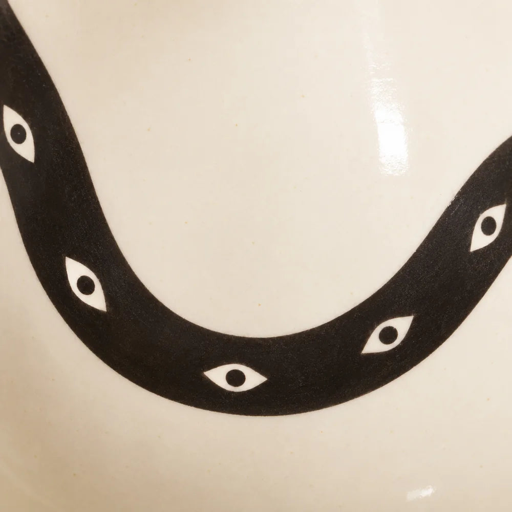 Dettaglio del serpente nero e dei motivi a occhio sulla ceramica avorio di Incantesimo.