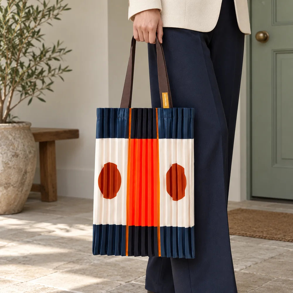 Tote blu scuro e arancio portata in mano, con la fascia centrale e i cerchi ruggine visibili.