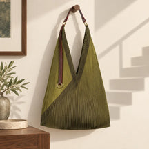 Borsa verde oliva in un interno chiaro, accanto all’ombra di una scala impossibile.