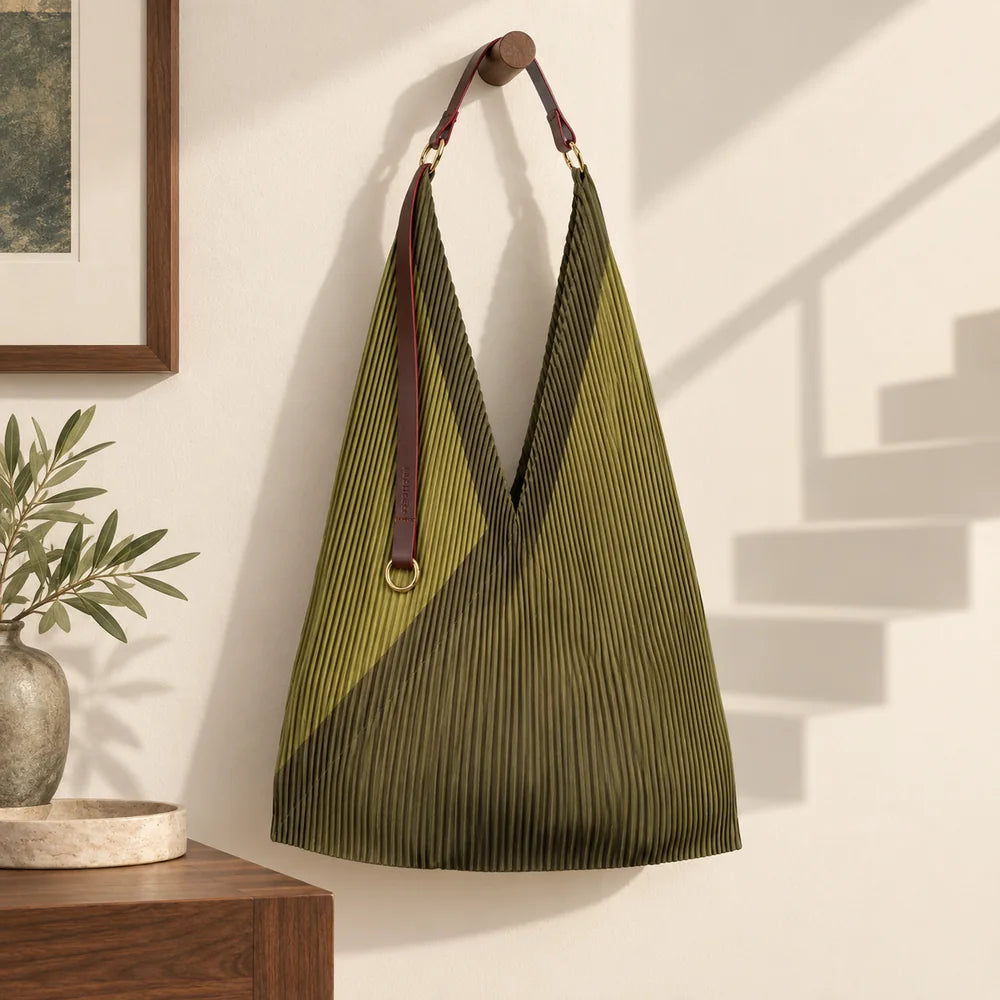 Borsa verde oliva in un interno chiaro, accanto all’ombra di una scala impossibile.