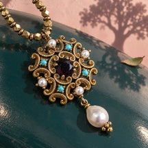 Pendente Isabella in ottone decorato, con cristallo scuro, accenti turchesi e perla pendente, su lacca petrolio.