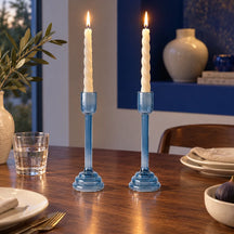 Due portacandele Soffio in vetro azzurro su una tavola apparecchiata, con candele decorative non incluse.