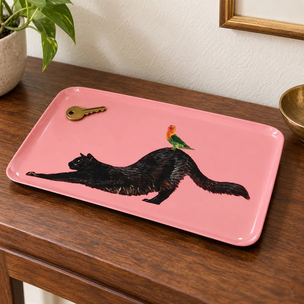 Svuotatasche rosa su una console in noce, con una chiave appoggiata in un angolo.